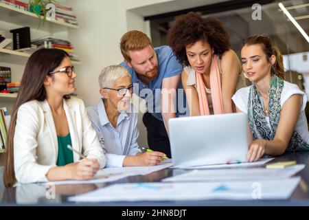 Team of happy successful architects working on construction plans in office. Stock Photo