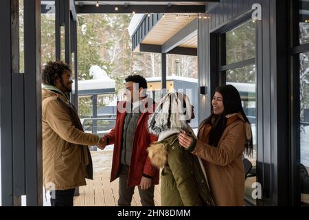 Group of friends greeting each other before the entrance of the house in the countryside in winter Stock Photo
