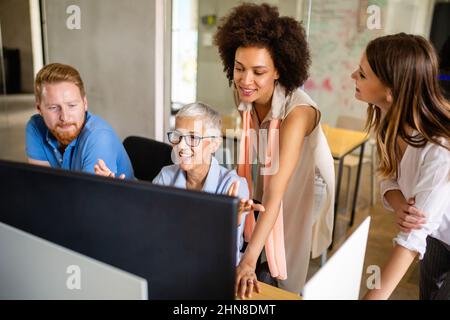 Group of software engineers working developing applications together in corporate office Stock Photo