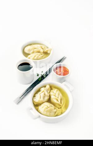 Dumplings are served in white cups with sauces on a serving board . Top view. Copy space. isolated Stock Photo