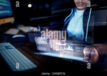 Your network has been breached. Shot of an unidentifiable hacker using a digital tablet in the dark. Stock Photo