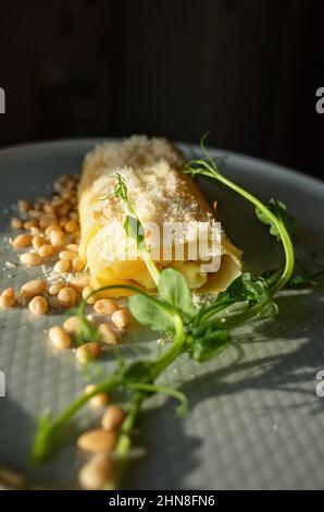Omelette with green pea sprouts and pine nuts, dramatic sunlight Stock Photo