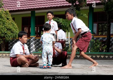 Lampung, Indonesia, December 17 2021- Elementary school children playing in the schoolyard wearing red and white clothes at a public Stock Photo