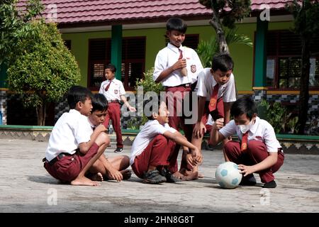 Lampung, Indonesia, December 17 2021- Elementary school children playing in the schoolyard wearing red and white clothes at a public Stock Photo