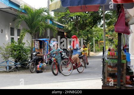 Lampung, Indonesia, December 17 2021-  two Indonesian children cycling in the afternoon while chatting with their friends Stock Photo