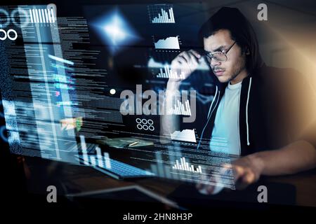 Encoding in progress. Shot of a young hacker cracking a computer code in the dark. Stock Photo
