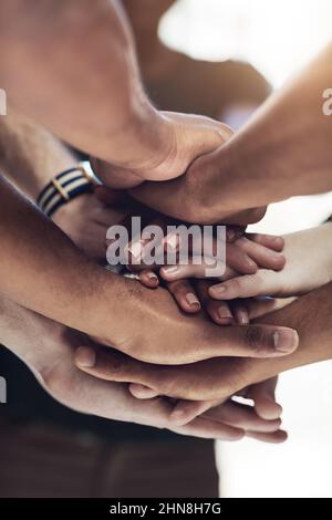 Were all connected. Cropped shot of a work group joining hands in solidarity. Stock Photo