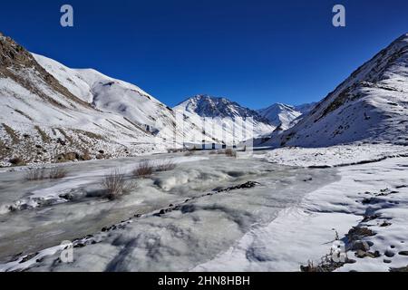 Road to Rumbak Valley and Yarutse, Hemis NP, Ladak, India. River with snow during winter, Himalayas. Mountain landscape in India wild nature. Sunny da Stock Photo