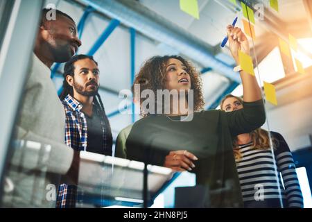 Sharing experience and expertise for an excellent brainstorming session. Shot of colleagues having a brainstorming session with sticky notes at work. Stock Photo