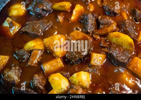 Cooking goulash with beef, potatoes, tomato and paprika in deep frying pan at home kitchen. Food photography Stock Photo