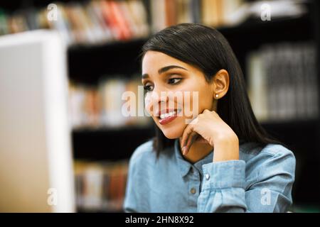 Shes a diligent student. Shot of a university student working on a computer in the library at campus. Stock Photo