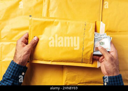 Male hands packing money in bubble envelopes for shipping. Stock Photo
