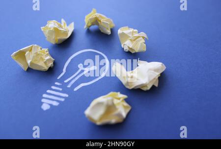 Lot of crumpled papers lying on drawn light bulb closeup Stock Photo
