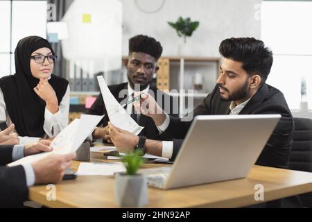 Team of diverse competent financiers showing graphs and charts on laptop during video conference. Company workers having online call with director or colleagues at office. Stock Photo
