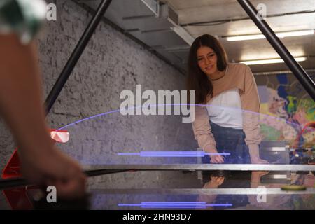 Lovely female student enjoying playing air hockey at college campus leisure room Stock Photo