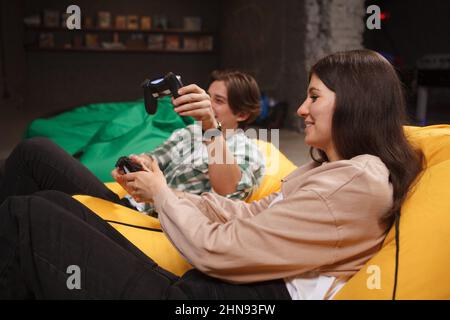Young beautiful woman smiling, playing video games with her boyfriend Stock Photo