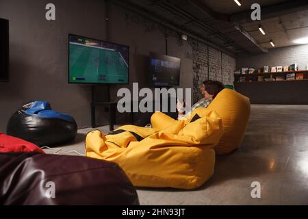 Rear view shot of two friends sitting in beanbag chairs enjoying playing video games Stock Photo