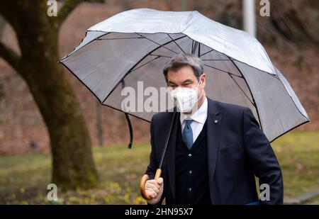 Munich, Germany. 15th Feb, 2022. Markus Söder (CSU), Prime Minister of Bavaria, arrives under an umbrella at the press conference after the cabinet meeting. Credit: Sven Hoppe/dpa/Alamy Live News Stock Photo