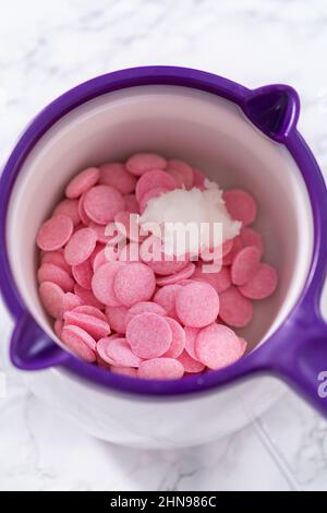 Melting pink chocolate melts to make mini pink chocolates Stock Photo -  Alamy