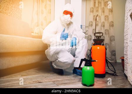 Exterminator in work clothes showing thumbs up. Fight against insects in apartments and houses. Disinsection of premises Stock Photo