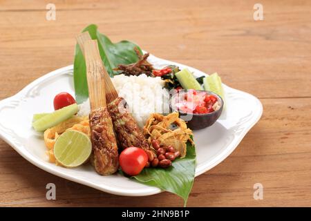 Nasi Lemak or  Nasi Campur Bali, Indonesian Balinese Rice with Sate Lilit, Ayam Sisit, Sambal Matah, and Peanut Stock Photo