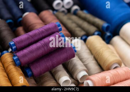 Multi-colored sewing threads laid out in a row. Bright background. Purpul Stock Photo