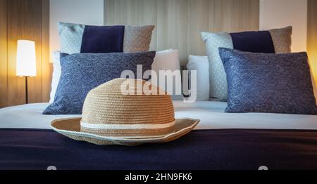 Summer hat on luxury bed. Travel and vacation concept. Stock Photo