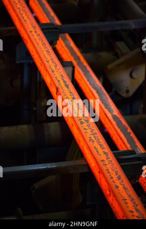 Low depth-of-field. Manufacturing of mild steel square bar on continuous casting machine. Ready hot metal bars. Stock Photo