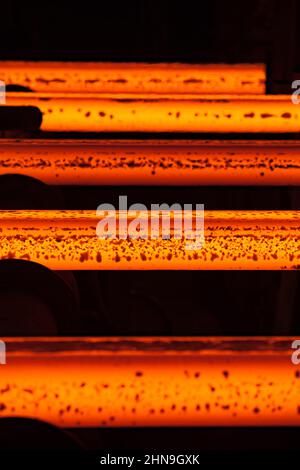 Manufacturing of mild steel square bar on continuous casting machine. Ready hot bars with slag pieces. Stock Photo