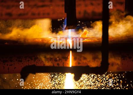 Manufacturing of mild steel square bar on continuous casting machine. Cutting bars by gas torch, close-up photo. Stock Photo