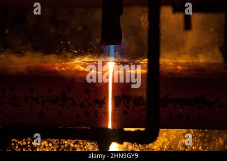 Manufacturing of mild steel square bar on continuous casting machine. Cutting bars by gas torch flame. Stock Photo