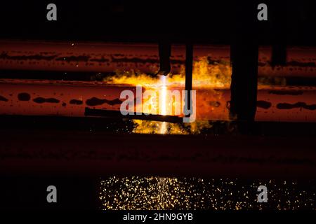 Manufacturing of mild steel square bar on continuous casting machine. Cutting bars by gas torch. Close-up photo. Stock Photo