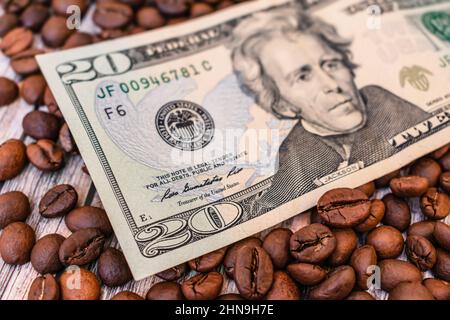 A banknote lies on the grains of roasted coffee, symbolizing the rise in price or reduction in the cost of natural coffee. Twenty dollars lie on grain Stock Photo