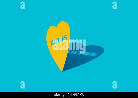 closeup of a yellow heart with the text thank you written in finnish, on a blue background Stock Photo