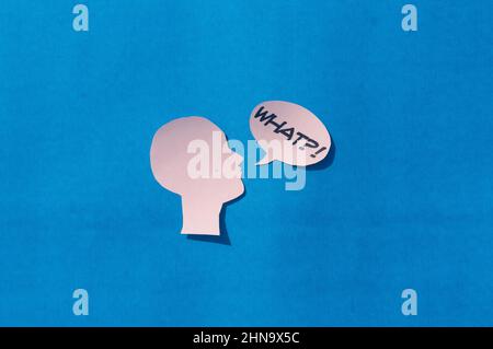 Paper Human face with What Question Mark on speech bubble isolated on blue background. Conceptual images showing to express doubt or uncertainty about Stock Photo