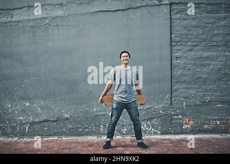 Take to the streets. Shot of a young man holding a skateboard outside. Stock Photo