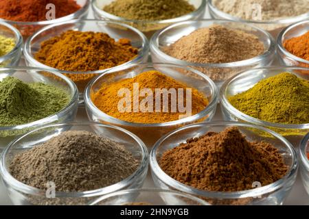 Glass bowls with variation of colorful powder herbs close up full frame as background Stock Photo