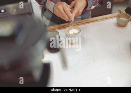 Male barista drawing pattern on milk foam Stock Photo