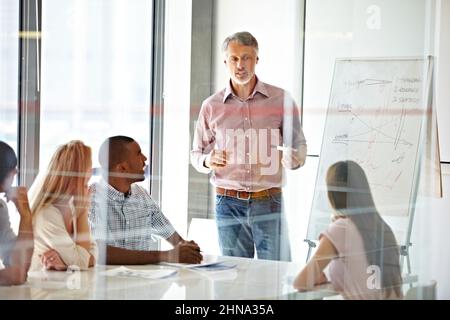 Sharing his experience and teaching them about business. Shot of a businessman presenting his ideas to his colleagues during a meeting. Stock Photo