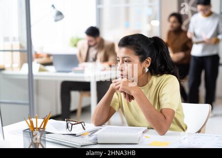 Serious businesswoman sitting at her workplace with documents with pensive expression, she working hard at office Stock Photo