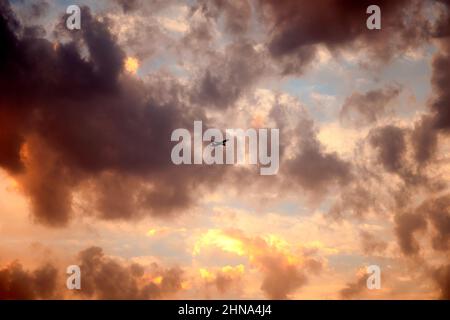 Beautiful sunset sky above clouds with dramatic light. Cabin view from airplane. the plane is flying in the clouds. Stock Photo