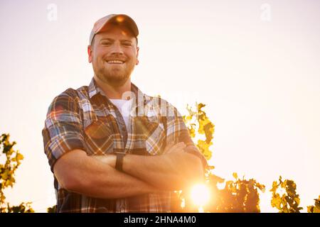 Im the master of this vineyard. Portrait of a happy farmer posing with his arms crossed in a vineyard. Stock Photo