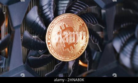 Golden coin with bitcoin symbol spinning on a GPU fan. Cryptocurrency mining theme Stock Photo