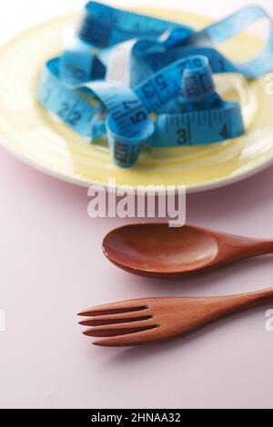 plate with measurement tape and cutlery on wooden background Stock Photo