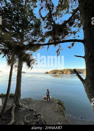 Female and dog posing on a cliff at Deception Pass State Park Stock Photo