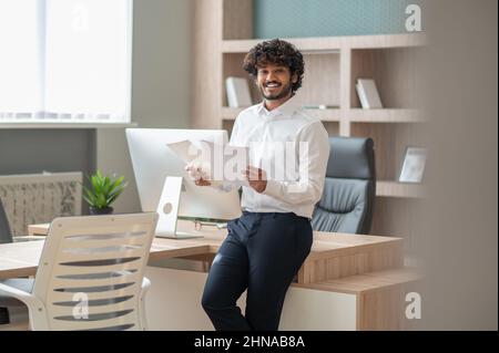 Young curly-haired manager feeling busy at work Stock Photo