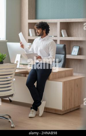 Young curly-haired manager feeling busy at work Stock Photo
