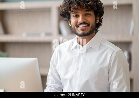Young curly-haired manager feeling busy at work Stock Photo