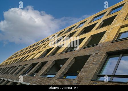 Oblique view on modern brown brick stone facade with many windows against blue sky with cumulus cloud - Maastricht, Netherlands Stock Photo