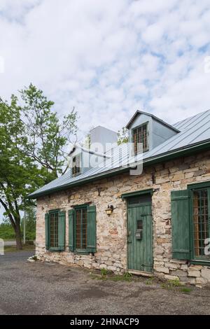 Old circa 1750  fieldstone house known as the Maison Labelle with grey standing seam sheet metal roof and green wooden glass pane windows. Stock Photo